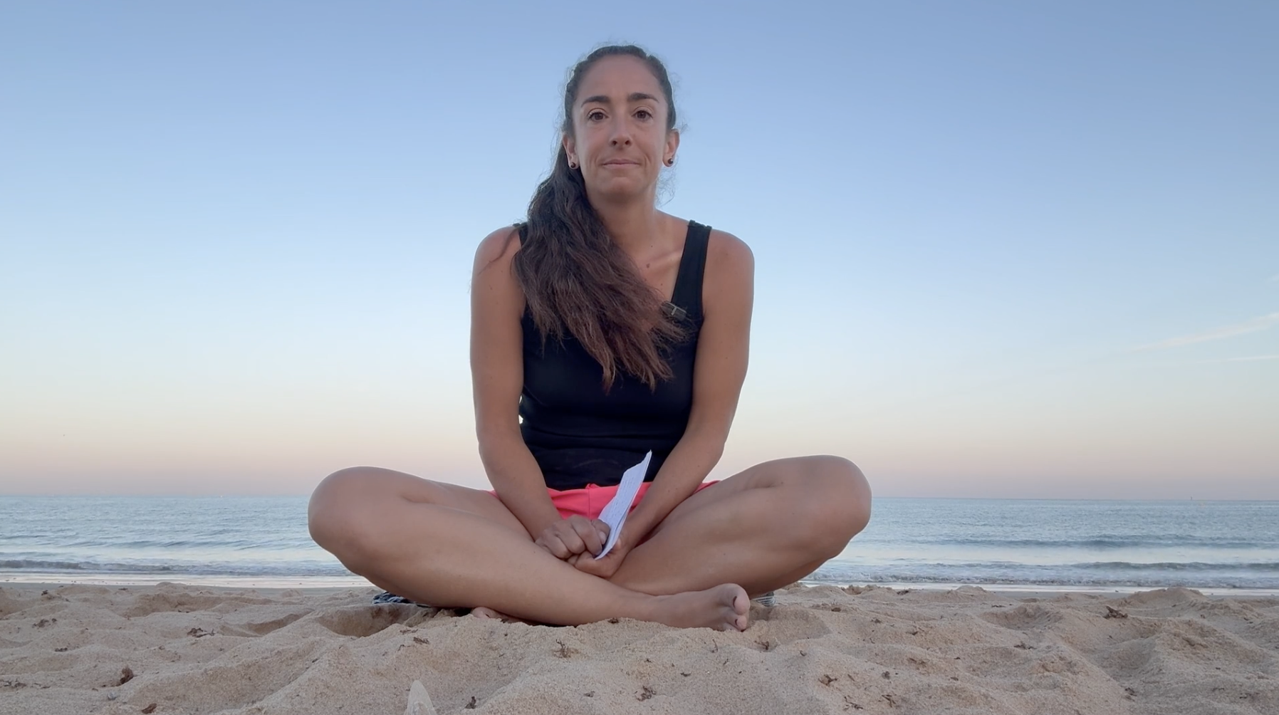 Margaux Magnée assise en tailleur sur une plage au crépuscule